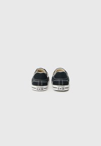 Tenisky Converse All Star slip-on v námořnické plátno s bílými gumovými podrážkami, s kontrastním šitím a logem na patě.