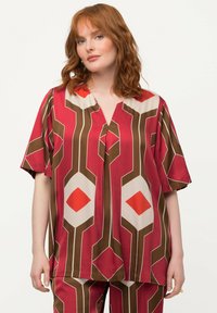 Kurzarmpbluse in Rot, Braun und Creme mit geometrischen Mustern und V-Ausschnitt, aus leichtem Stoff gefertigt.