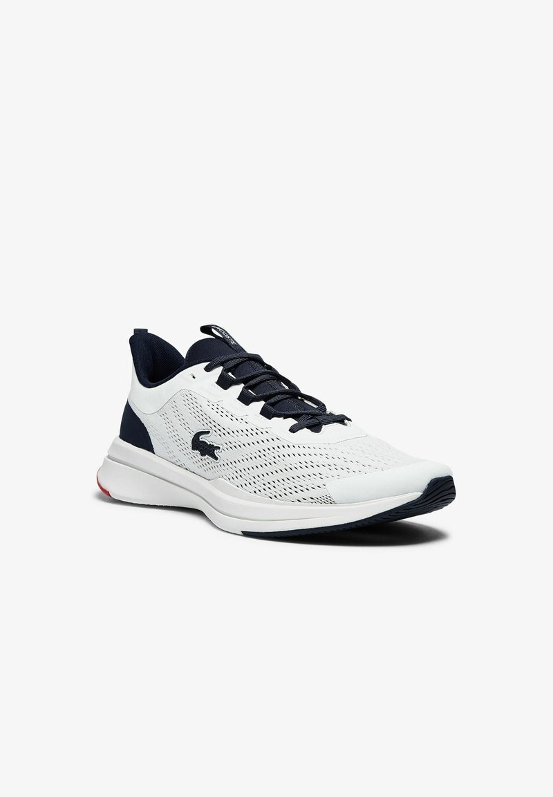 Vit atletikssko med en andningsbar mesh-överdels, marinblå detaljer, platta snöre och en vadderad sula med en röd detalj på hälen.