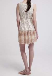 Floral-patterned, tiered dress features a lace top in ivory, with a fitted waist and a flowing, sheer skirt in pastel colors.