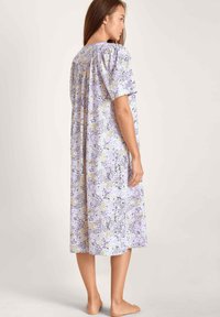Camisola floreale in lavanda, con maniche corte, scollatura rotonda e una vestibilità ampia con schiena arricciata. Motivo floreale orizzontale.