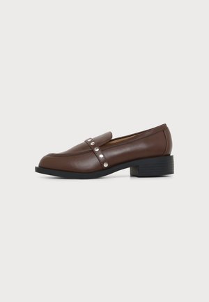 Hnedý kožený mokasín s nízkym blokovým podpätkom a remienkom so štyrmi striebornými nýtkami na boku na jednofarebnom pozadí.