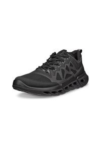 Chaussure de sport noire avec dessus en mesh, panneaux latéraux à motifs, semelle épaisse ventilée et lacets noirs, présentée légèrement de biais sur fond blanc.