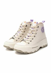 Zapatillas altas hechas de un tejido beige texturizado con acentos en púrpura claro, presentando un logo redondo, cordones de tela y suelas gruesas y estampadas.