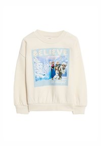 Crème kleuren sweatshirt met een ronde hals en elastische mouwen. Heeft een gedrukt ontwerp van figuren tegen een sneeuwachtige achtergrond met de tekst "GELIEVE in magie."