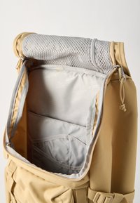 Μπεζ σακίδιο με ανοιχτό το επάνω καπάκι, που δείχνει εσωτερική επένδυση ανοιχτού γκρι και πολλαπλές εσωτερικές τσέπες, συμπεριλαμβανομένου ενός διαμερίσματος με φερμουάρ από δίχτυ.