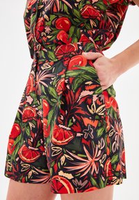 Pantalones cortos florales con fondo negro, que presentan vibrantes patrones en rojo y verde, diseño plisado y bolsillos laterales para un detalle adicional.