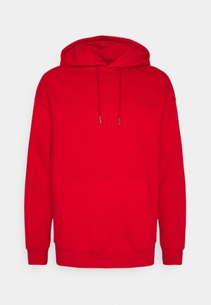 Sudadera con capucha roja fabricada en un tejido suave, que cuenta con un bolsillo frontal, cordones y puños de canalé. Textura suave con un color sólido.