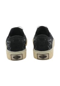 Baskets en toile noire avec un motif texturé et des accents blancs. Elles présentent un talon à motif, une semelle en caoutchouc et une étiquette de marque à l'arrière.