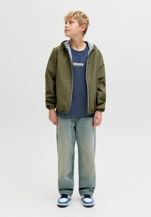 Zielona, za duża kurtka z kapturem, szara podszewka, zestawiona z niebieskim t-shirtem z napisem "BANGKOK", jasnoniebieskimi dżinsami i niebieskimi trampkami.