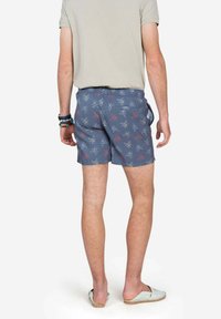 Bañador azul con un estampado de pulpos y calaveras. Tejido ligero, de longitud hasta el muslo, con cinturilla elástica y bolsillo en la parte posterior.