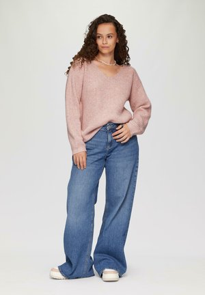 Lichtroze geribbelde trui met V-hals en lange mouwen, gecombineerd met wijde blauwe denim jeans en witte plateau schoenen.