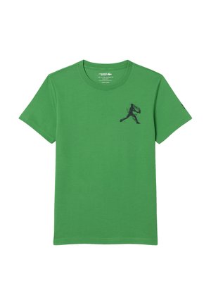 T-shirt en coton vert avec des manches courtes et un col rond. Comprend un graphique en silhouette noire d'une figure en train de courir sur le côté gauche de la poitrine.