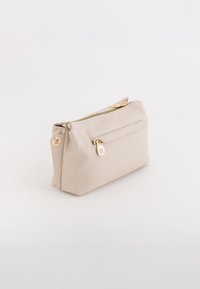 Beżowa torebka z syntetycznej skóry z złotym zamkiem błyskawicznym, przednią kieszenią i zaokrąglonymi krawędziami, z dodatkowymi złotymi elementami.