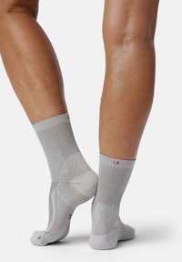 Calcetines deportivos grises con un diseño de malla texturizada, de longitud hasta el tobillo, con talones reforzados y un pequeño logotipo en la parte superior de cada calcetín.