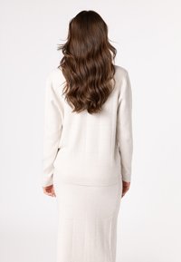 Light beige ribbed sweater dress features long sleeves and a fitted shape, with a textured square pattern and ribbed hem accents.
