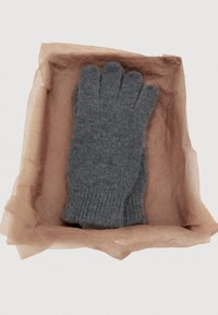 Gray fingerless glove made of knitted wool, featuring a ribbed cuff, displayed on crumpled brown wrapping paper in a flat position.