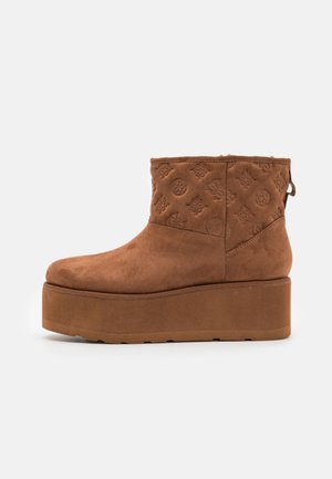 Bottine en daim marron avec semelle plateforme et motifs floraux embossés sur la tige supérieure, vue de profil sur fond blanc uni.