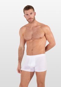 Bílé bavlněné boxerky s logem v pase, které mají hladkou, jemnou texturu a přiléhavý střih, který zvýrazňuje tvar.