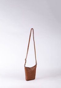 Brown leather crossbody bag with a slim, rectangular shape, adjustable strap, and a front pocket featuring subtle detailing.