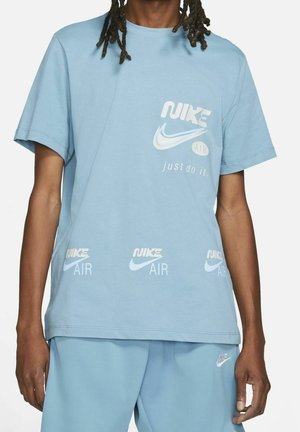 T-shirt en coton bleu clair avec le logo Nike, comprenant les inscriptions "NIKE AIR" et "just do it." imprimées en blanc. Manches courtes et coupe décontractée.