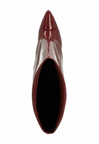 Bottine en cuir verni bordeaux avec un bout pointu et une texture lisse et brillante, présentant une tige ouverte et une doublure intérieure noire.