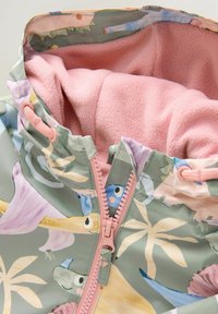 Leichte Jacke mit einem pastellgrünen Äußeren, das mit floralen und Cartoon-Motiven verziert ist. Rosa Fleece-Futter und kontrastierender Reißverschluss mit Kordelzug-Toggles.