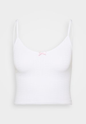 Witte crop top met dunne bandjes, textuurpatroon en een roze strikdetail in het midden. Zachte stof en getailleerde pasvorm.