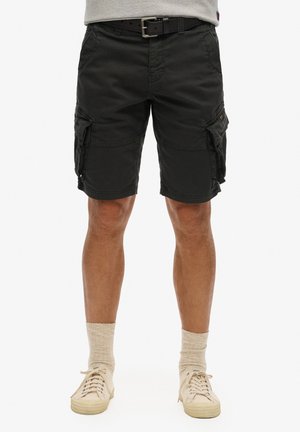 Zwarte cargoshorts met meerdere zijzakken, riemlussen en een duurzame stof. Gemaakt met beige sneakers en lichtgekleurde sokken.