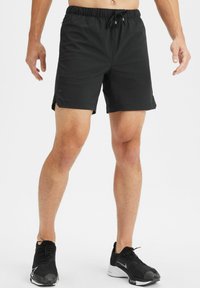 Schwarze Sportshorts mit elastischem Bund und Kordelzug. Leichtes Material, seitliche Schlitze für mehr Bewegungsfreiheit und glatte Textur.