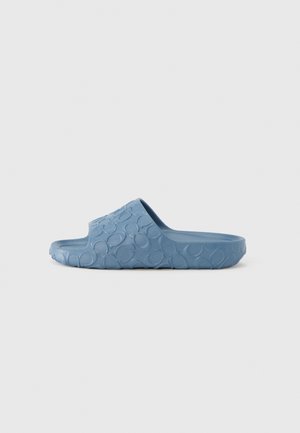 Blue slide sandal made of textured rubber, featuring a wave-like pattern on the sole and a wide, open strap design for breathability.