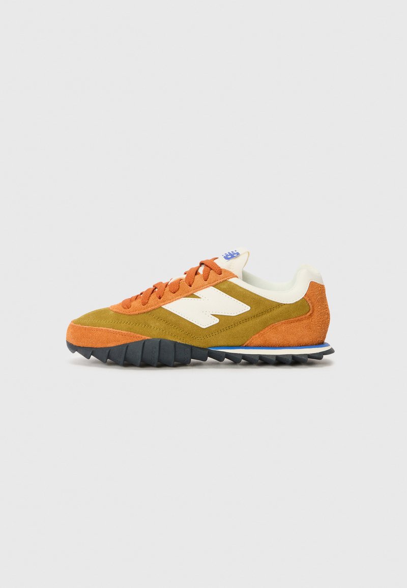 Zapatillas de ante con paneles en naranja, verde y blanco, que presentan una puntera texturizada y una suela negra estriada para mayor tracción.