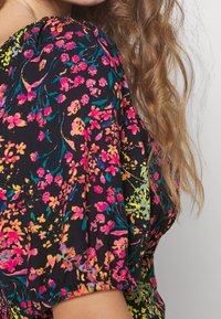 Robe à motifs floraux, à manches courtes, avec un fond noir ; présente des fleurs roses vives, jaunes et vertes ; tissu doux avec un décolleté froncé.