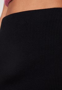 Zwarte geribbelde gebreide rok met een gladde textuur, met een hoge taille en rekbaar materiaal voor een strakke pasvorm.