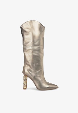 Botte métallique dorée jusqu'au genou avec un bout pointu et un haut angulaire. Présente un talon bloc distinctif avec un accent géométrique.