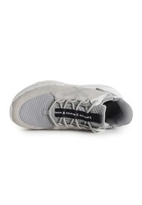 Zapatilla deportiva gris que presenta una parte superior de malla texturizada y ante, puntera redonda, diseño de cordones y una marca en la lengüeta en negro contrastante.