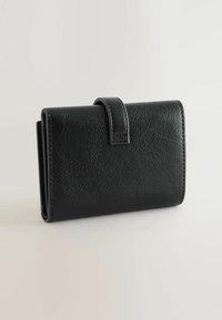 Portefeuille en cuir noir avec une surface texturée, comportant un rabat replié et des accents cousus, de forme rectangulaire compacte.