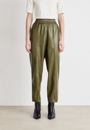 Olive green faux leather pants with an elasticated waistband, featuring a loose fit and smooth texture, paired with pointed black ankle boots.