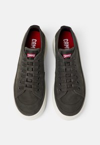 Sneaker grigie scure con tomaia in pelle liscia, punta rotonda e suola in gomma bianca. Presentano lacci, logo rosso e dettagli di cucitura discreti.