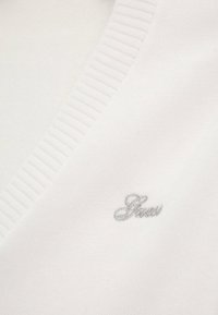 Pull en tricot blanc avec un col en V et des bords côtelés. Doté d'un logo brodé gris subtil sur le côté gauche. Texture douce avec de fins détails.