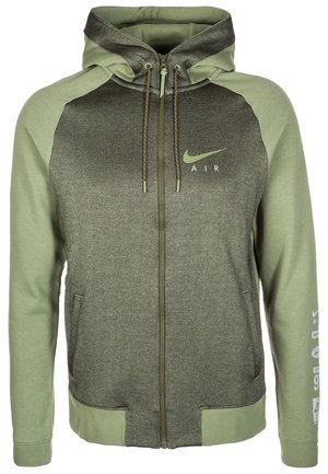 Sweat à capuche zippé avec manches et capuche vert olive, panneau avant plus foncé, logo Nike Air sur la poitrine et texte imprimé sur la manche gauche.