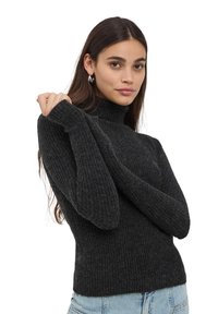 Maglione a coste grigio scuro con collo alto, maniche lunghe e design aderente, abbinato a jeans in denim azzurro chiaro.