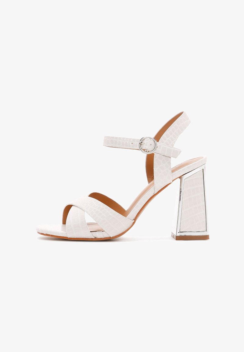 Sandales à talons blanches en cuir avec motif crocodile, dotées d'un talon rectangulaire épais, comportant deux brides croisées et une bride de cheville avec une boucle métallique.
