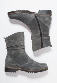 Bottes chelsea en suede gris avec un design flasque, fermeture éclair latérale et surface texturée. Dotées d'une semelle en caoutchouc noir avec un léger talon.