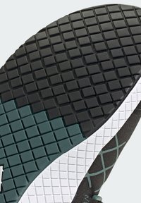 Shoe sole featuring a black textured rubber surface with a grid pattern, a teal accent, and a white edge along the side.