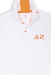 Polo bianco con un accento arancione sul colletto, caratterizzato da due forme ricamate arancioni e tre bottoni arancioni. Tessuto testurizzato.