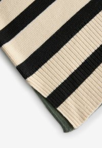 Gestreifter Strickstoff mit abwechselnden schwarzen und cremefarbenen Streifen; strukturmuster mit einem grünen Untergrund am Rand.