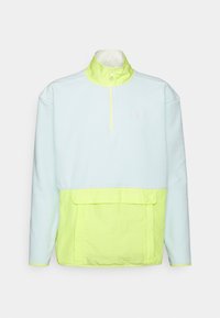 Pullover a mezzo zip realizzato in tessuto morbido; presenta una parte superiore azzurro chiaro e una parte inferiore neon verde brillante, con una tasca frontale e chiusura con zip.