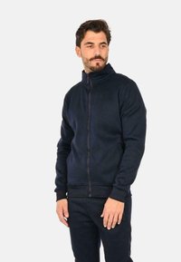 Felpa con zip blu navy e colletto alto, con polsini e fondo a costine, realizzata in tessuto morbido. Presenta una zip frontale completa e tasche laterali.