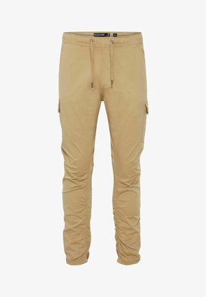 Pantalones cargo beige fabricados en material suave, con cintura ajustable, bolsillos laterales y puños fruncidos. Presentan un diseño de pierna ajustada.